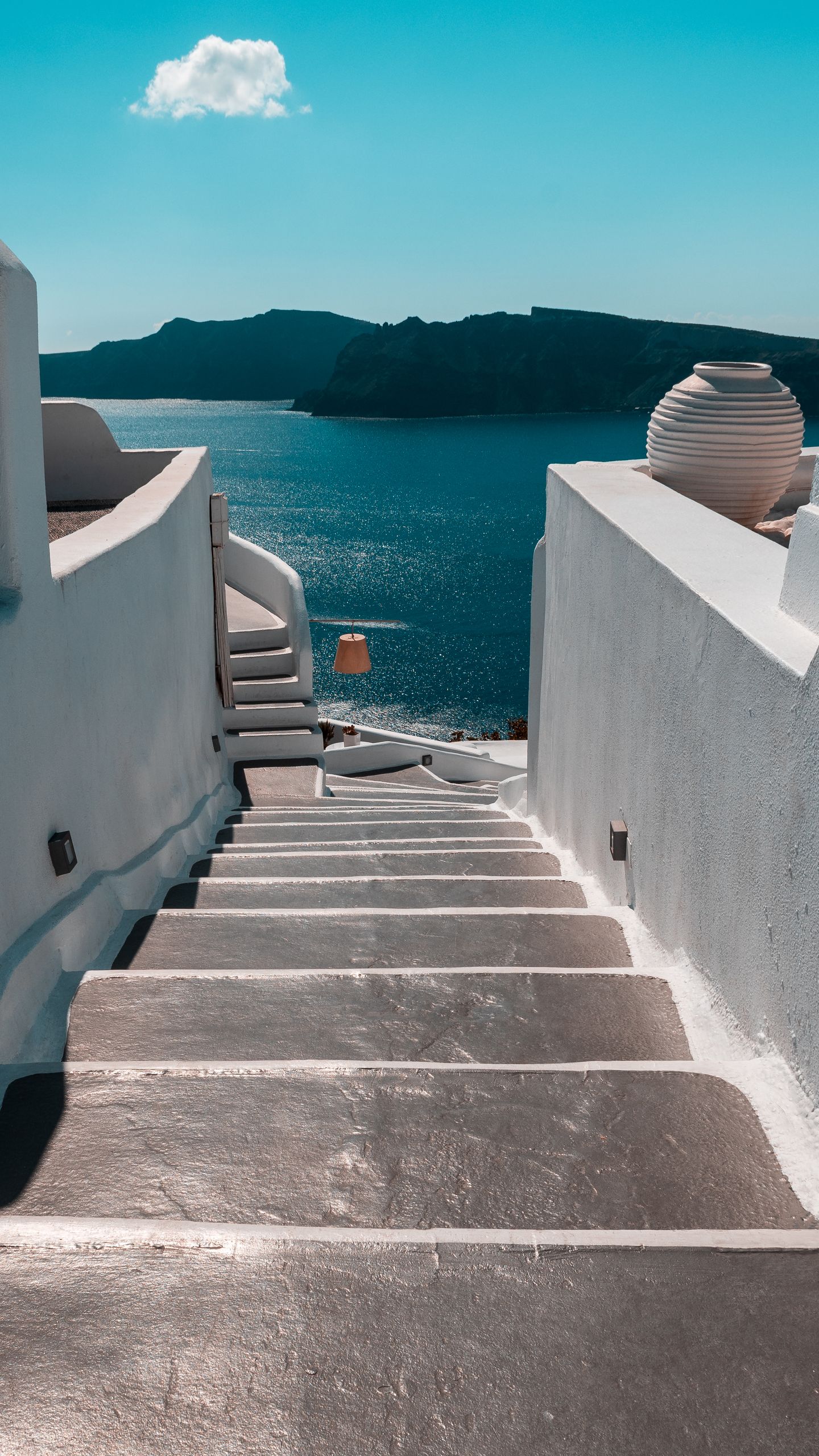 A stunning view of white steps leading to the Aegean Sea in Thera, Greece under a clear blue sky.